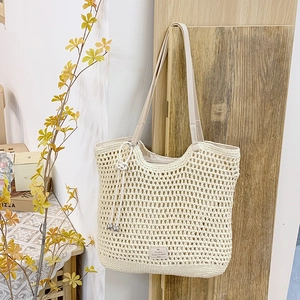 Detail of cream woven tote bag featuring hollow crochet texture and leather shoulder strap