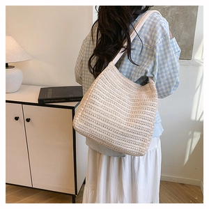 Detail of a beige woven tote bag with texture showing capacity on model's shoulder