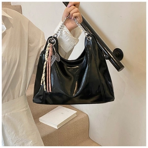 Detail of glossy black tote bag featuring silver chain strap and tennis racket charm