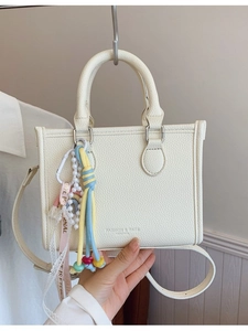 Chic beige lychee leather handbag with colorful charms and adjustable shoulder strap
