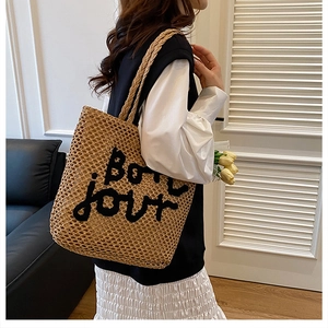 Détail du sac cabas en paille tissée avec broderie Bon Jour porté par un mannequin