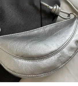 Close-up of metallic silver crescent bag with pleated texture and knotted strap detail