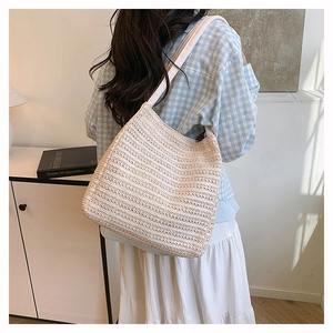 Detailed view of beige woven tote bag with horizontal texture and wide shoulder strap
