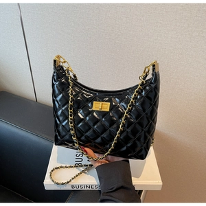 Close-up of black glossy patent leather crossbody bag with quilted rhombic pattern and gold chain