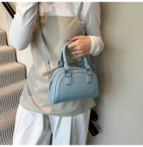 Détail du sac bowling bleu clair en cuir grainé avec ferrures argentées et poignées