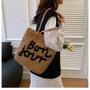 Détail du sac cabas en paille tissée avec broderie Bon Jour noire et texture fine