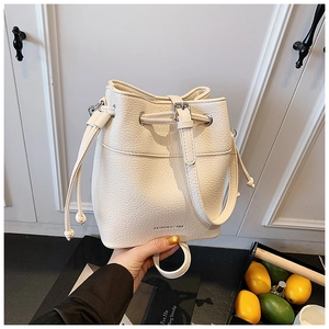 Detail view of cream-white bucket bag with lychee grain texture and drawstring closure