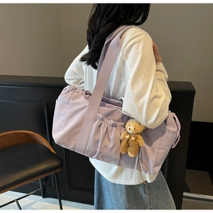Detail of lavender large canvas tote bag with drawstring folds and teddy bear pendant