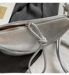 Detail view of smooth silver zipper and pleated metallic texture on the crescent bag