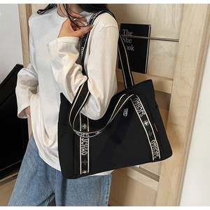 Detail of the large black tote bag with SJCHAO striped handles and side pocket