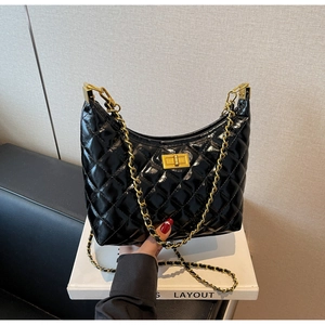 Detail of black quilted leather shoulder bag with gold chain strap and turn-lock closure