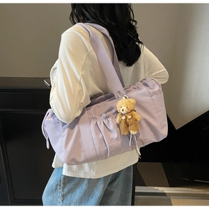 Detail of lavender canvas tote bag featuring front pleats and a cute teddy bear charm