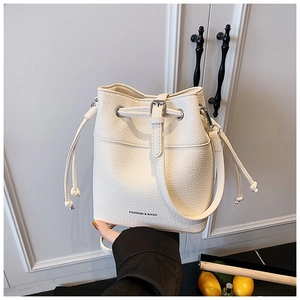 Detail of beige bucket bag featuring lychee grain leather and drawstring closure