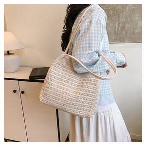 Close-up of hand-woven tote bag with leather straps and striped hollow pattern design
