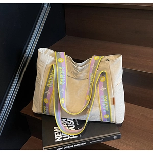 Detail of beige tote bag with patterned jacquard strap on a wooden staircase