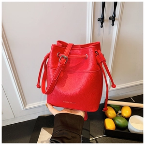 Detail of red water-ripple textured bucket bag with drawstring closure and silver hardware