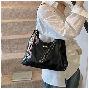 Detail of glossy black hobo bag with pink tassel charm and tennis racket pendant