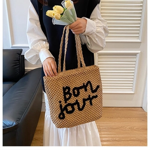 Détail du sac fourre-tout en paille tissée avec broderie Bonjour pour les vacances d'été