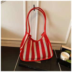 Close-up of a red and white striped mesh tote bag with leather straps on a casual table
