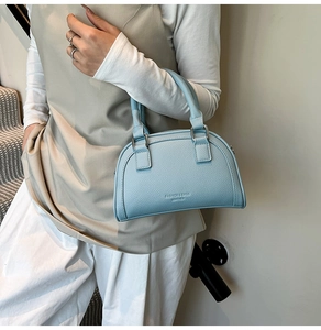 Détail du sac bowling bleu clair avec texture de cuir grainé et boucles argentées