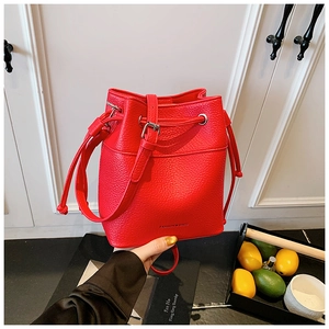 Detail of red bucket bag showing litchi grain leather texture and drawstring closure