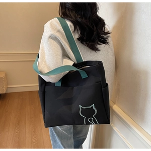 Detail view of large canvas tote bag with teal shoulder straps and cat embroidery