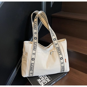 Detail of wide woven strap and side pocket on large off-white nylon tote bag