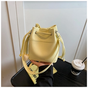 Detail of light yellow bucket bag with pebbled leather texture and drawstring closure