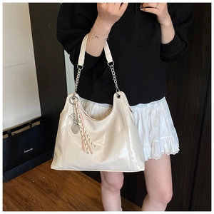 White patent leather tote bag featuring a silver chain strap and tennis racket charm