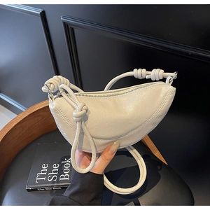 Dettaglio borsa a mezzaluna crema in pelle martellata con cinturino a nodo decorativo