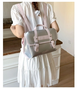 Silver metallic backpack with pink trim and double buckle closure worn by a model