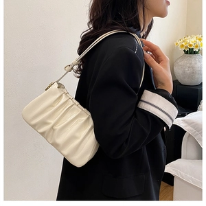 Close-up of cream white pleated cloud bag with soft leather texture and slim strap