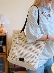Chic beige hand-woven crochet tote bag with black leather straps and silver bead charms