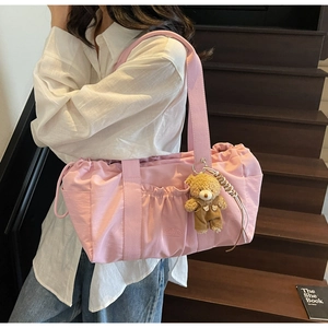 Pink nylon tote bag detail featuring a pleated front pocket and cute teddy bear charm accessory