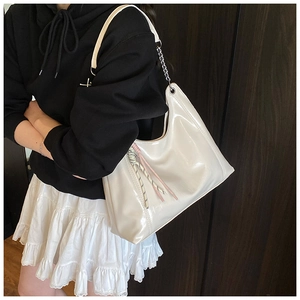 Detail of cream oil wax leather tote bag featuring metal chain strap and woven rope tassel