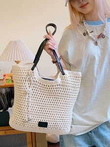 Large woven tote bag with black leather straps and hollow mesh design for beach holidays