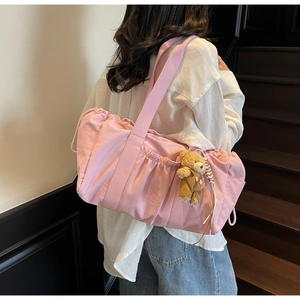 Detail of pink pleated canvas bag with wide strap and cute bear charm pendant