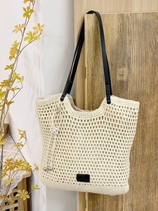 Beige crochet beach tote bag with black straps and decorative knot for women