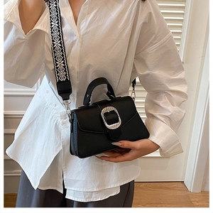 Detail der schwarzen Handtasche aus Leder mit Silberschnalle und Muster-Tragegurt