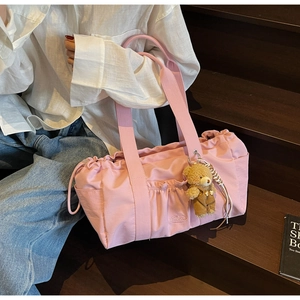Detailed shot of pink nylon tote bag featuring elastic ruched pockets and teddy bear charm