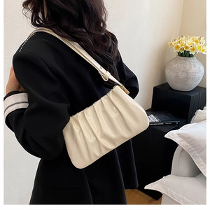 Detail of a creamy beige pleated cloud bag with shiny finish and golden metal buckle
