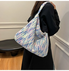 Detail der farbenfrohen Stricktasche mit Stoffetikett an einer Person in Schwarz