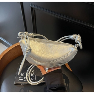 Dettaglio della borsa a mezzaluna argento con nodi decorativi e trama metallica