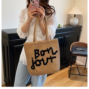 Détail du sac cabas en paille tressée avec broderie Bonjour noire style de plage