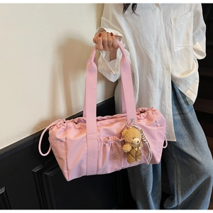 Detailed view of pink nylon tote bag with drawstring closure and cute teddy bear charm