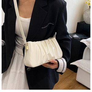 Detail of a creamy white pleated cloud bag with soft leather texture and thin strap