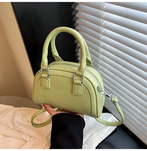Gros plan détaillé du sac boston vert citron en cuir grainé avec finitions argentées