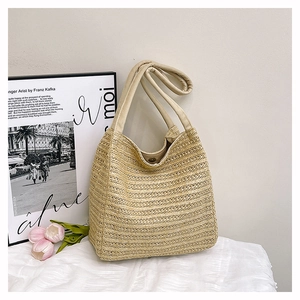 Close-up of beige woven straw tote bag with fabric handles on artistic background