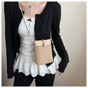 Detail of woven straw phone bag featuring a pearl clasp and beige leather flap