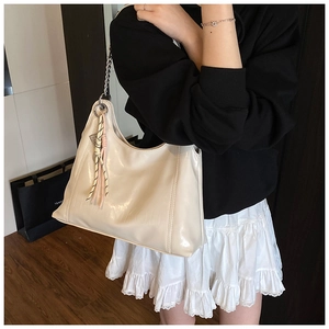 Detailed close-up of cream glossy tote bag featuring silver chain and woven pendant detail
